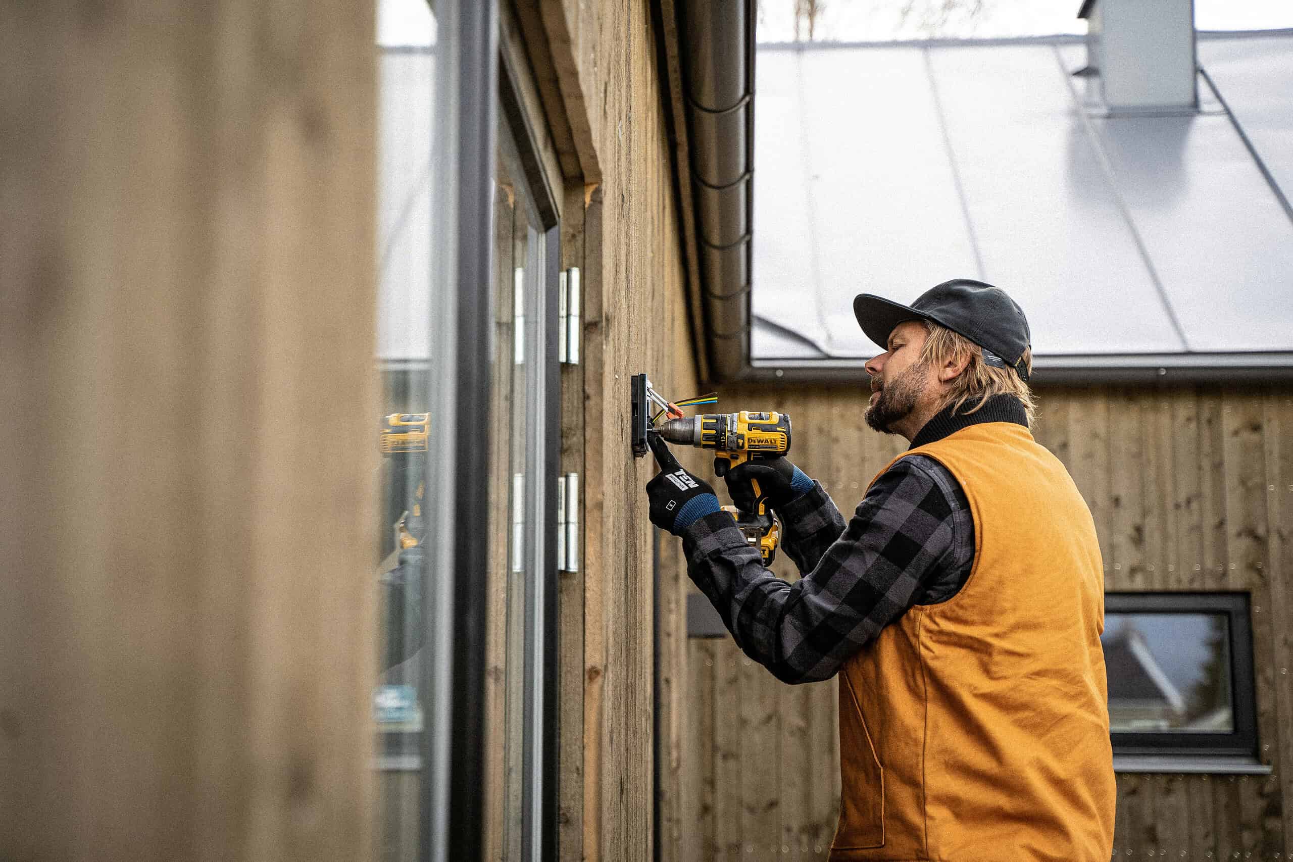 Electrician securing a light fixture to a house - wall sconce